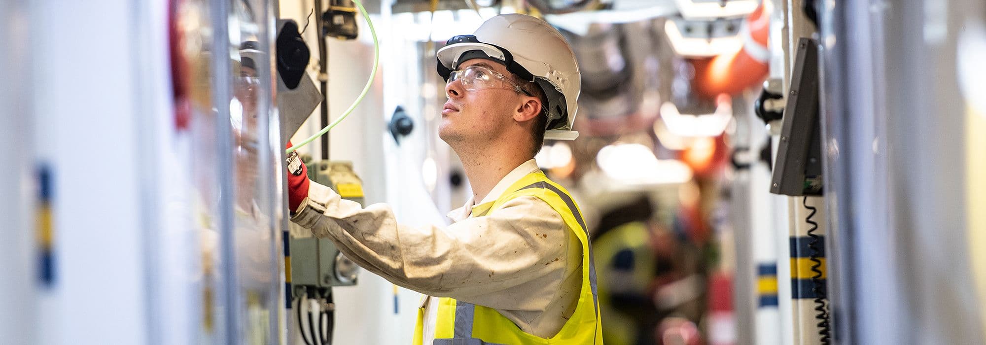 A man is working in hard hat and visibility vest