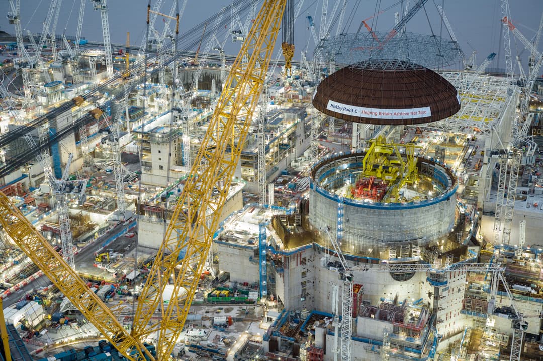 Aerial view of Hinkley Point C, a large nuclear power station construction site with cranes, scaffolding and a reactor dome being lifted into place