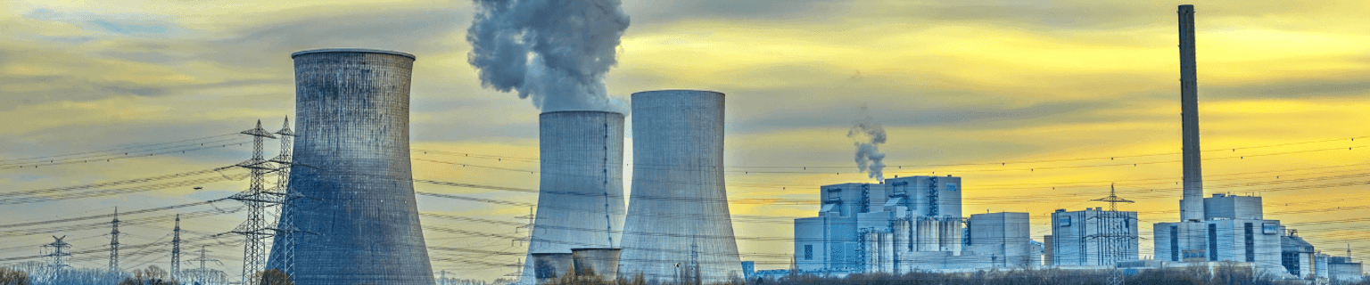 Cooling towers and industrial buildings of a power station with steam rising against a cloudy sky