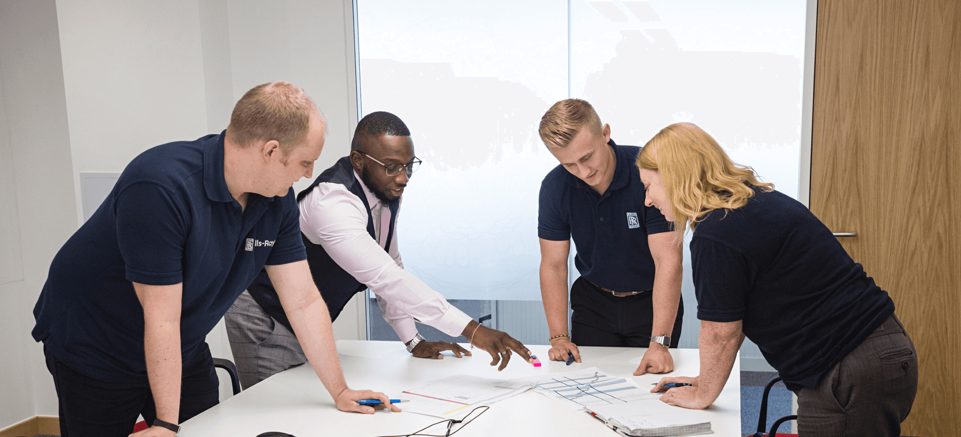 Group of people discuss papers in a meeting room